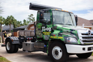 A JDog Junk Removal & Hauling Savannah/HHI dumpster truck parked on a residential street.