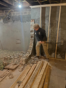 A JDog Junk Removal & Hauling Concord, NC team member performing demolition work on a brick wall as a labor service.