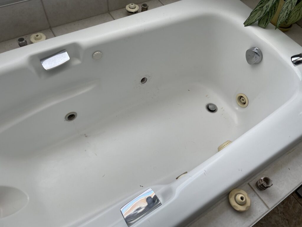 A jetted bathtub undergoing repair or maintenance, with parts around the edges, by GCB Home Improvement in Appleton, WI.