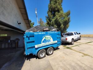 A Junk Away & Cleaning trailer full of various household items and debris, parked in a driveway in Sacramento, CA.