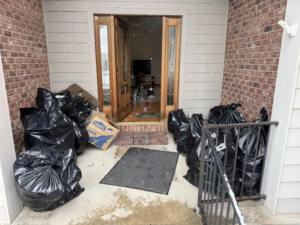 Black trash bags and a Lowe's box piled by a front door, ready for junk removal by Greybeard Dumpster Rentals in Morgantown, WV.