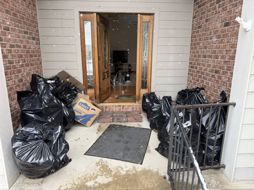 Black trash bags and a Lowe's box piled by a front door, ready for junk removal by Greybeard Dumpster Rentals in Morgantown, WV.
