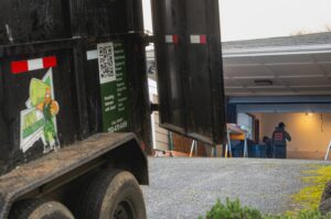A Junk Commandos trailer backed up to a garage, ready for loading debris during a junk removal job in Tacoma, WA.