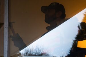 A reflection of a Junk Commandos worker performing demolition with a hammer during a junk removal service in Tacoma, WA.