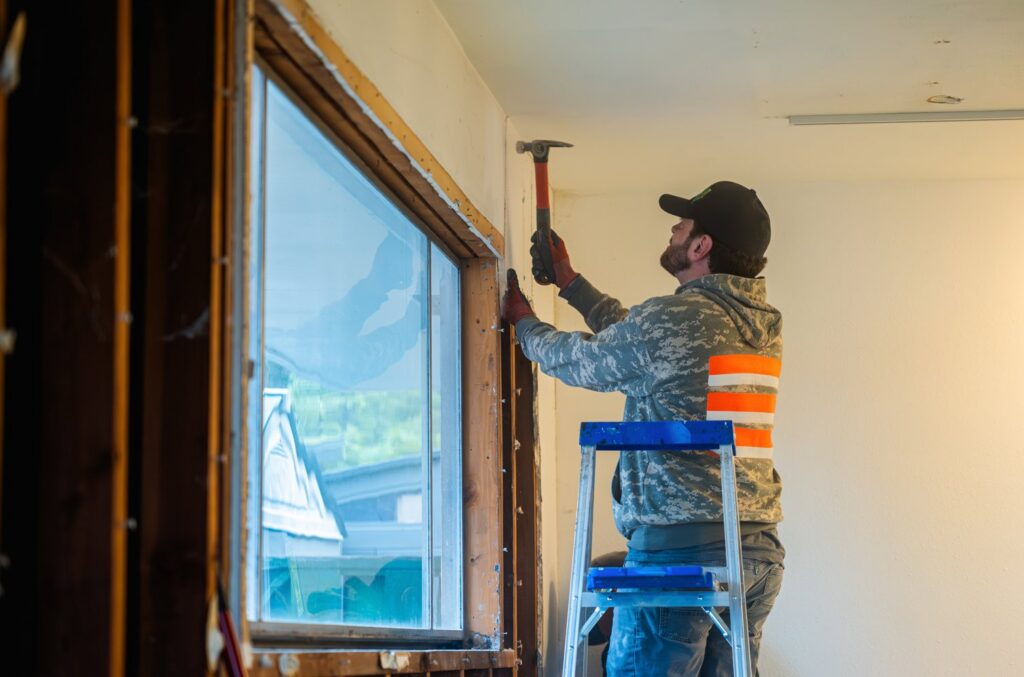 A Junk Commandos team member removing window trim with a hammer during a demolition and junk removal project in Tacoma, WA.