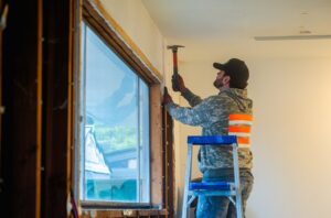 A Junk Commandos team member removing window trim with a hammer during a demolition and junk removal project in Tacoma, WA.