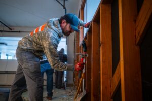 A Junk Commandos team member removing wood framing with a hammer during a demolition and junk removal project in Tacoma, WA.