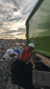 A Junk It OR Dump It worker in Independence, MO, at a landfill, preparing to unload a junk removal truck.