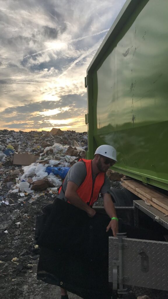 A Junk It OR Dump It worker in Independence, MO, at a landfill, preparing to unload a junk removal truck.