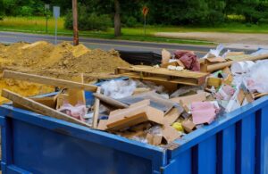 A blue roll-off dumpster filled with various types of junk and debris, ready for pickup by Rhode Island Disposal in Providence, RI.