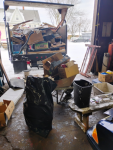A truck bed overflowing with various junk and boxes, with more debris on the ground, handled by Cox Junk & Debris Removal in Buffalo, NY.