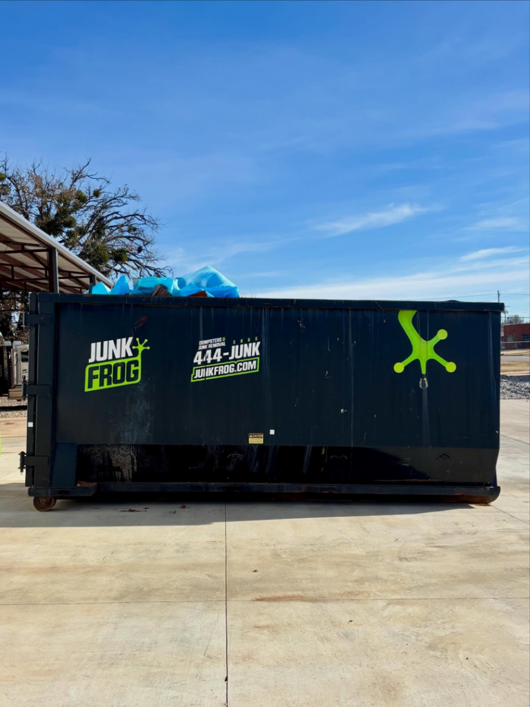 A Junk Frog commercial dumpster partially filled with debris for junk removal in Oklahoma City, OK.