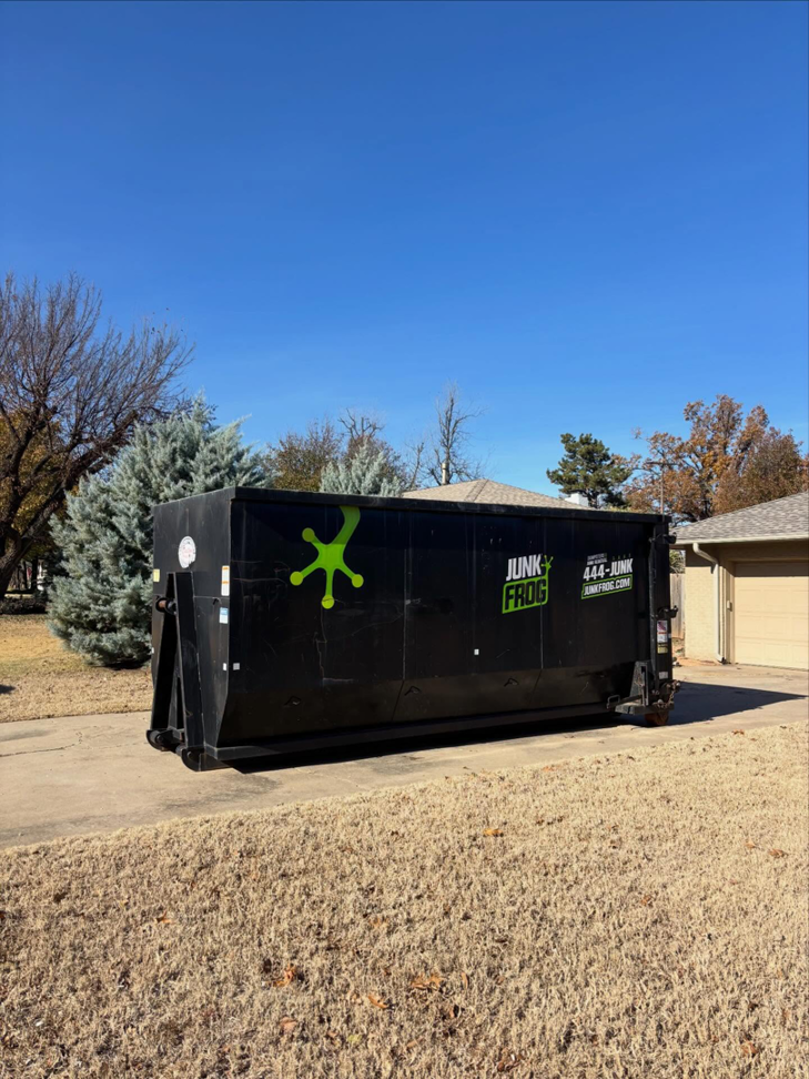 A Junk Frog dumpster on a residential driveway for home cleanout services in Oklahoma City, OK.