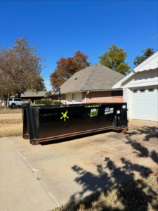 A Junk Frog roll-off dumpster placed on a residential driveway for junk removal services in Oklahoma City, OK.