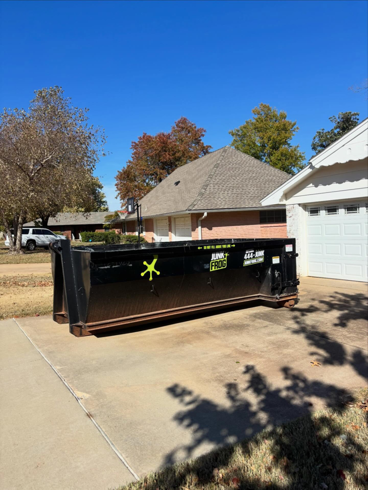A Junk Frog roll-off dumpster placed on a residential driveway for junk removal services in Oklahoma City, OK.