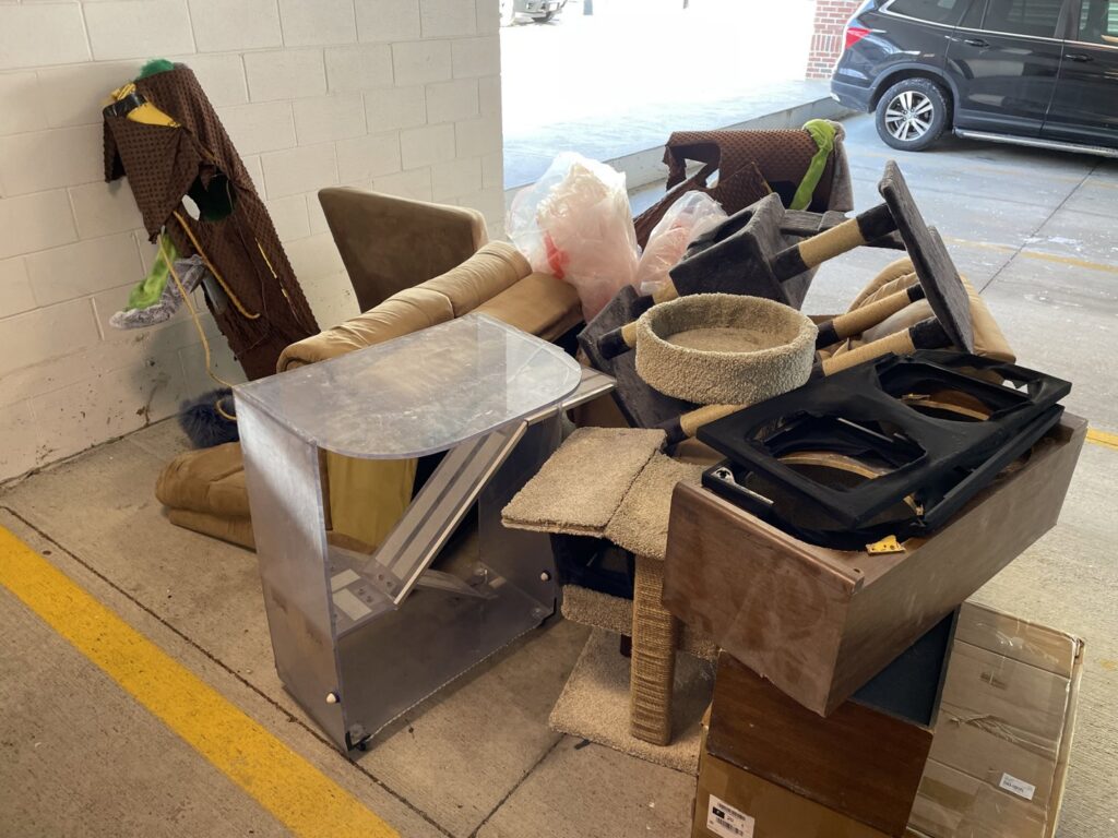 A large pile of old furniture and cat trees in a parking garage for Junk Dunkers in Wrentham, MA