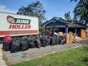 A Junk Holler truck parked next to a large pile of trash bags and cardboard boxes for removal in Boise, ID.