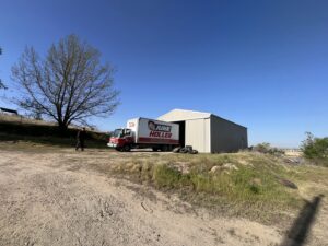 A Junk Holler truck parked next to a shed with old tires on the ground, ready for removal in Boise, ID.