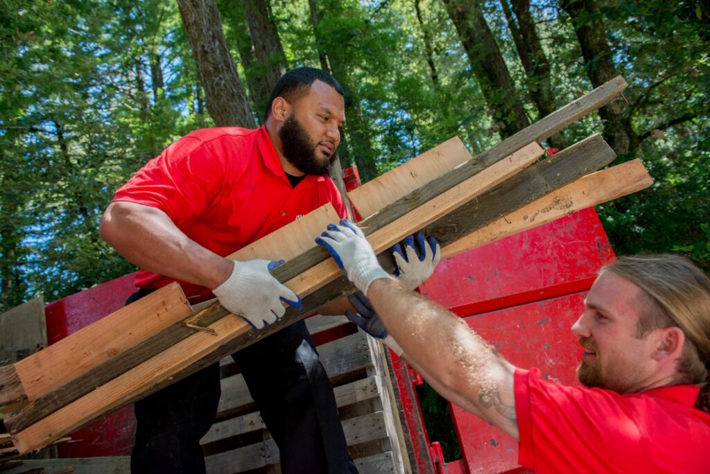 Junk King team members loading wood debris into a junk removal truck in Greensboro, NC.