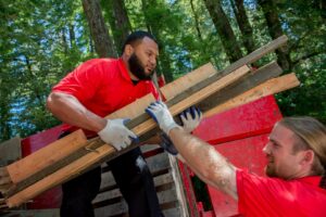 Junk King team members loading wood debris into a junk removal truck in Greensboro, NC.