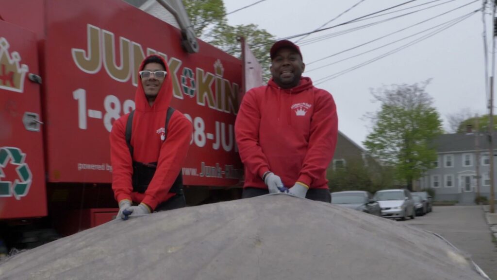 Two friendly Junk King team members standing in front of their junk removal truck in Greensboro, NC.