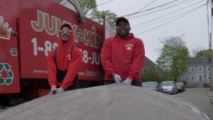 Two friendly Junk King team members standing in front of their junk removal truck in Greensboro, NC.