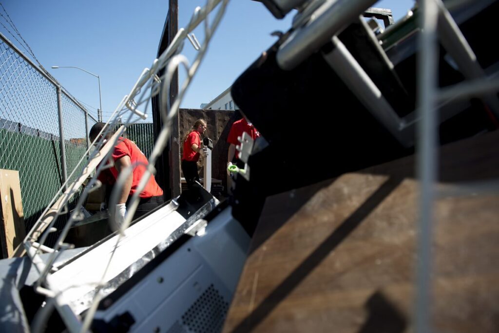 Junk King workers loading various debris and items into a junk removal truck in Greensboro, NC.