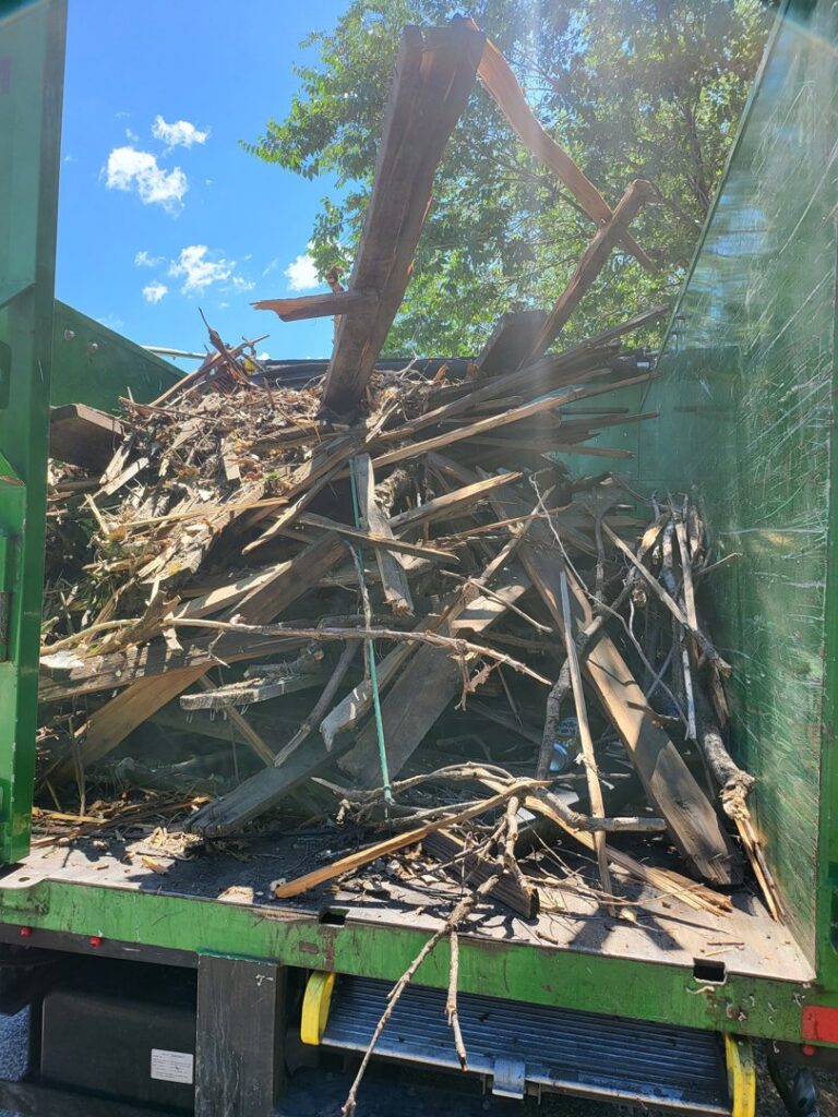 The back of a Junk Movers truck filled with wood debris, branches, and other waste after a successful junk removal job in Salt Lake City, UT.
