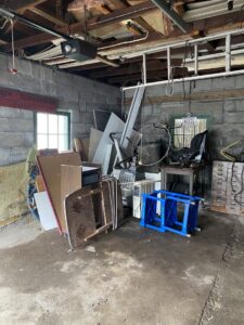 A large pile of miscellaneous junk and debris in a garage, ready for cleanout by Trash King LLC in Derry, NH.