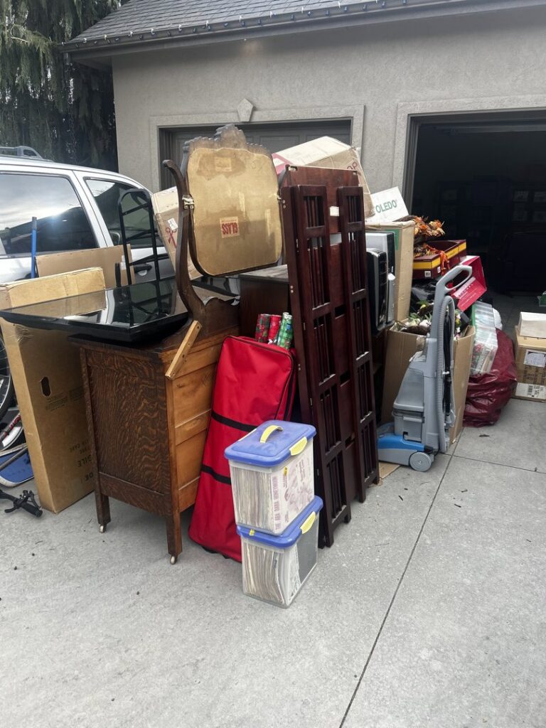 A pile of various household items and junk stacked outside a garage for Junk Holler to pick up in Boise, ID.
