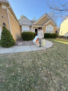 A Junk It OR Dump It employee in Independence, MO, carrying bags of items away from a residential home.