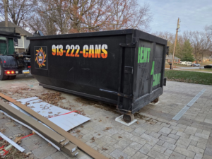 A KC TRASH GUYS LLC dumpster being delivered for junk removal on a residential driveway in Johnson county, MO.