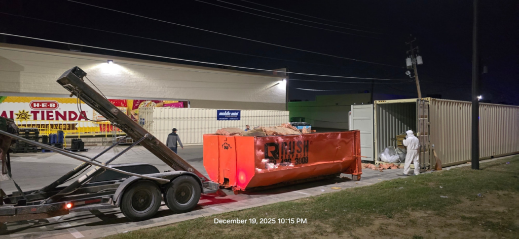 A Rush Disposal LLC team member loading a dumpster with debris onto a truck for junk removal in Laredo, TX.