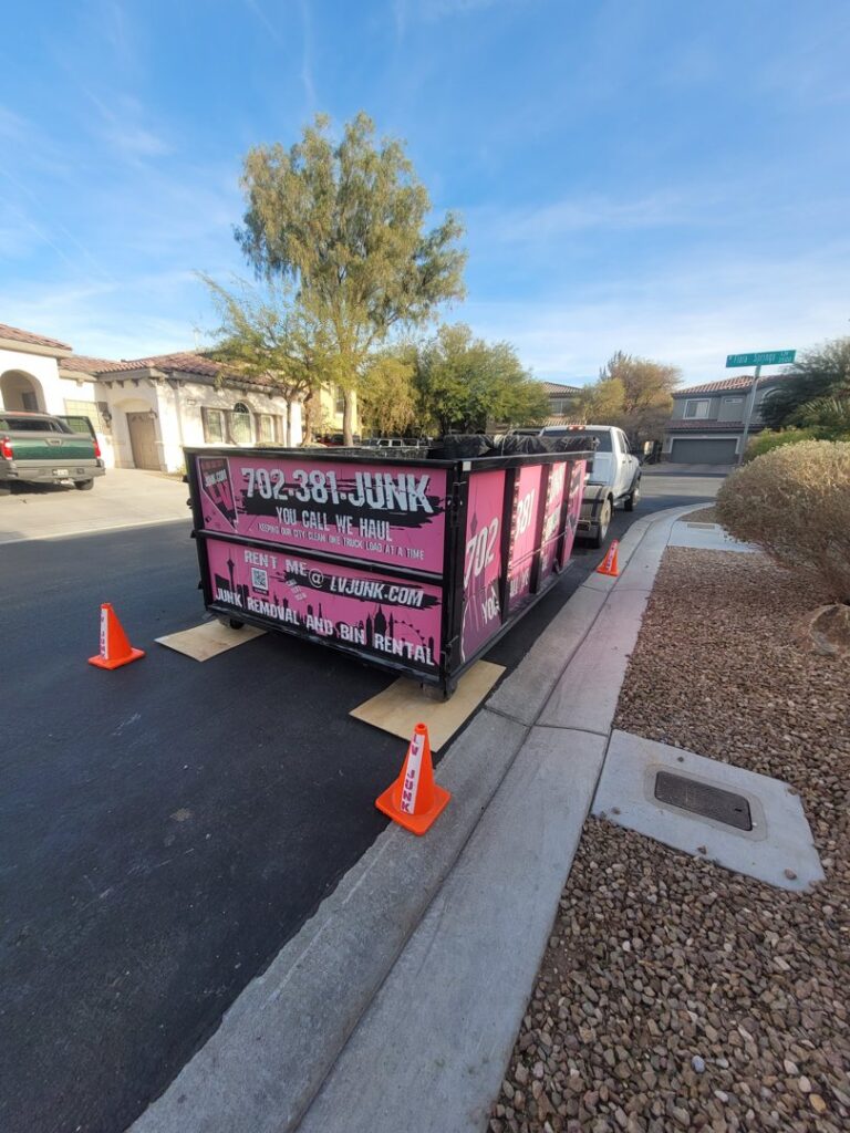 A pink branded junk removal dumpster from Las Vegas Hauling Junk & Moving placed on a residential street in Las Vegas, NV