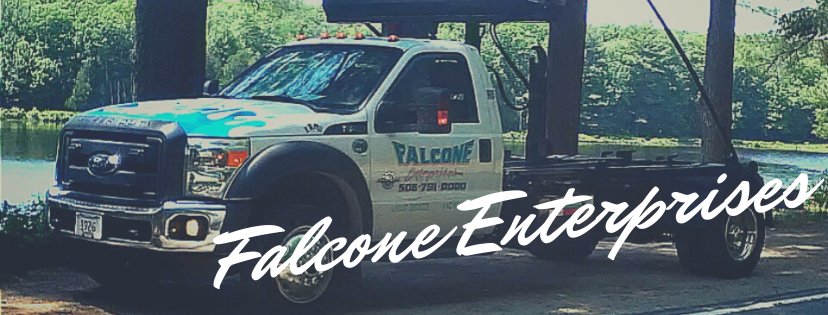 A Falcone Enterprises junk removal dumpster truck parked by a scenic lake in Worcester, MA.