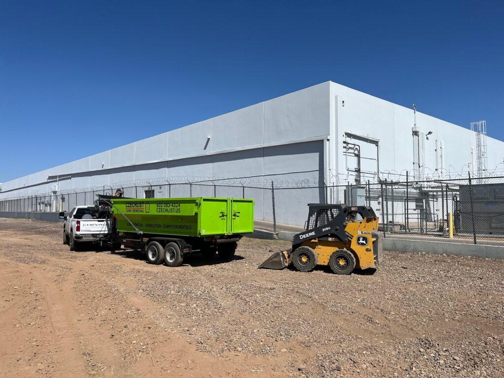 CzechList Junk Removal truck, trailer, and skid steer loader on a commercial job site in Scottsdale, AZ.