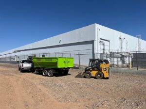 CzechList Junk Removal truck, trailer, and skid steer loader on a commercial job site in Scottsdale, AZ.
