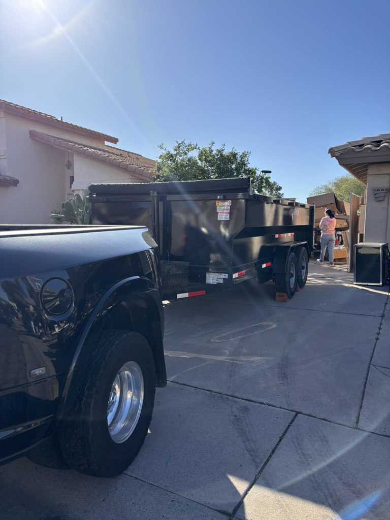 A dump trailer on a residential driveway with items ready for junk removal by Sunrise Mountain Hauling LLC in Peoria, AZ.