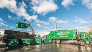 A Century Waste Management garbage truck and crane truck performing junk removal with multiple dumpsters in Sterling Heights, MI.