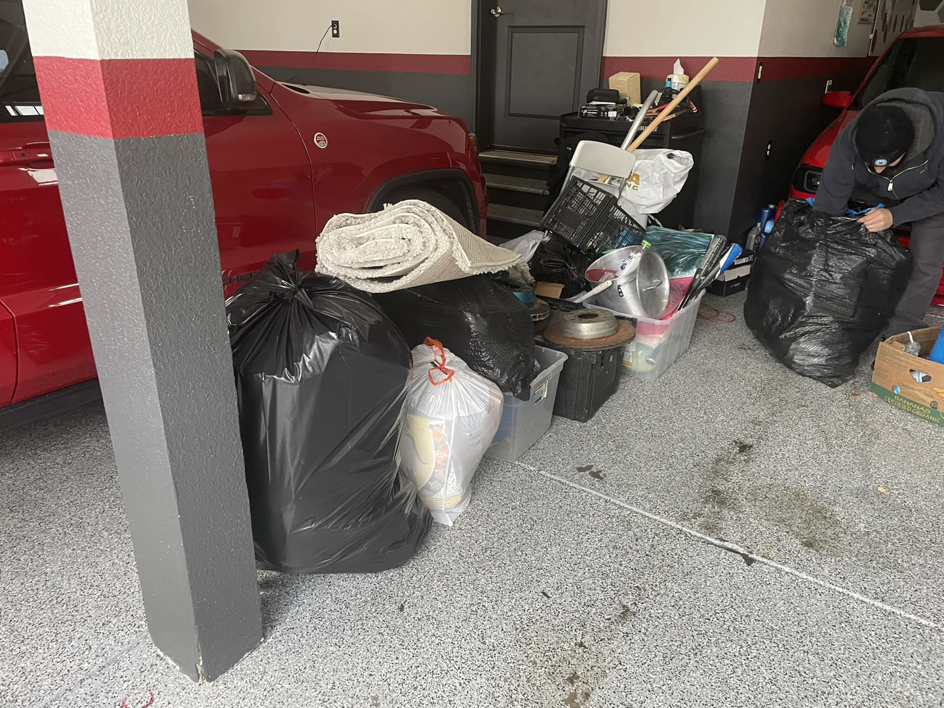 A person bagging junk and debris in a garage, preparing for a junk removal service by Denver Dumpsters in Denver, CO.