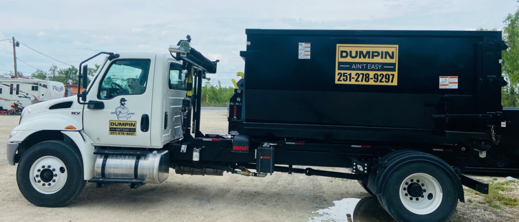 A branded junk removal roll-off truck with a black dumpster from Dumpin Ain't Easy in Westwego, LA.