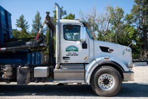 A white roll-off truck with a blue container for junk removal services by Evergreen Disposal in Kalispell, MT.