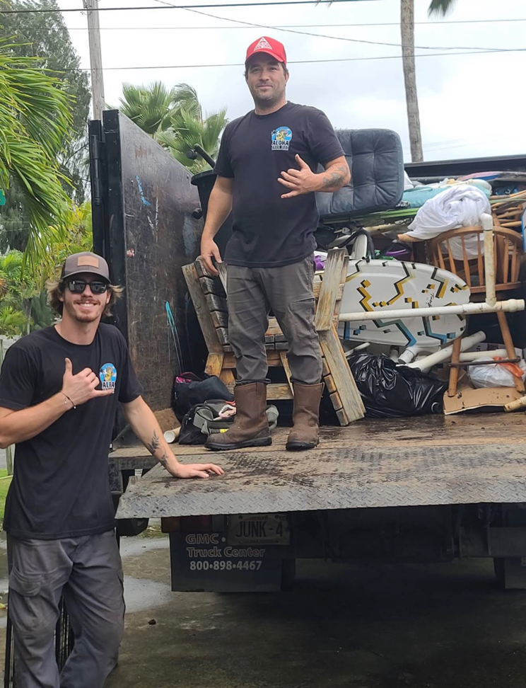 Two Aloha Junk Man team members standing with a truck full of removed junk and furniture in Kailua, HI.