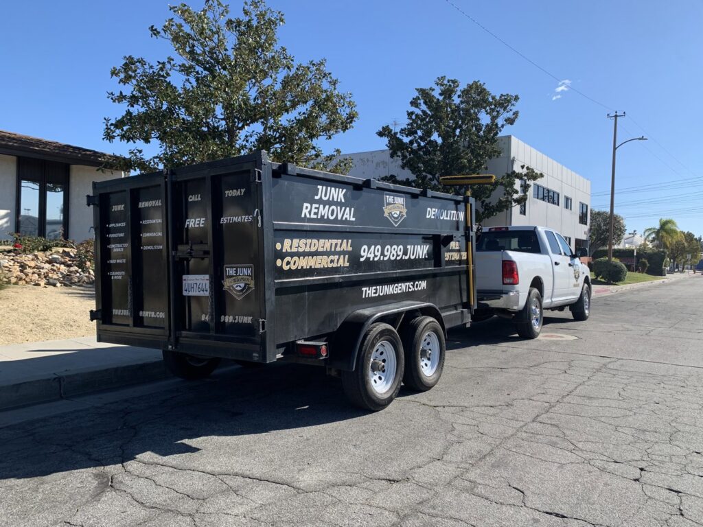 A branded junk removal trailer and truck from The Junk Gentlemen parked on a street in Anaheim, CA.