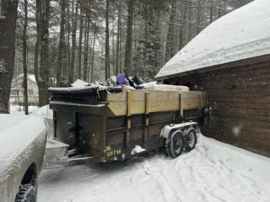 A junk removal trailer parked next to a house, filled with debris by CleanSite Solutions in Windham, ME.