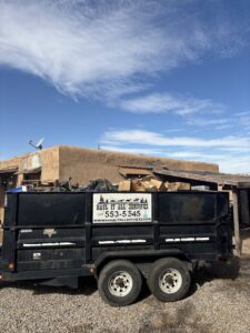 A Haul It All Services junk removal trailer full of debris parked outside a residential home in Albuquerque, NM