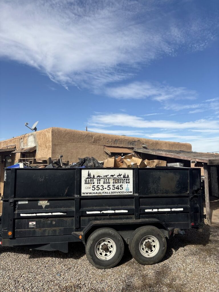 A Haul It All Services junk removal trailer full of debris parked outside a residential home in Albuquerque, NM