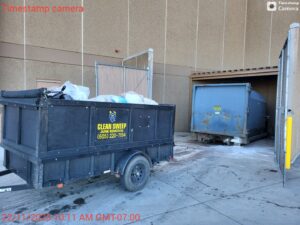 A Clean Sweep Junk Removal trailer full of trash bags and debris at a commercial site in Augusta, ME.
