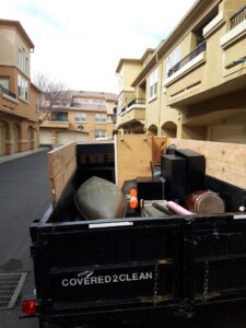 A Covered2Clean junk removal/hauling trailer loaded with various items, including a canoe, in Sacramento, CA.