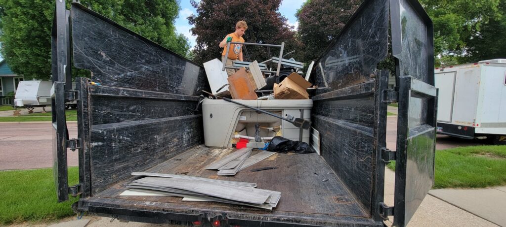 A dump trailer loaded with a hot tub, metal, wood, and other debris for junk removal in Sioux Falls, SD.